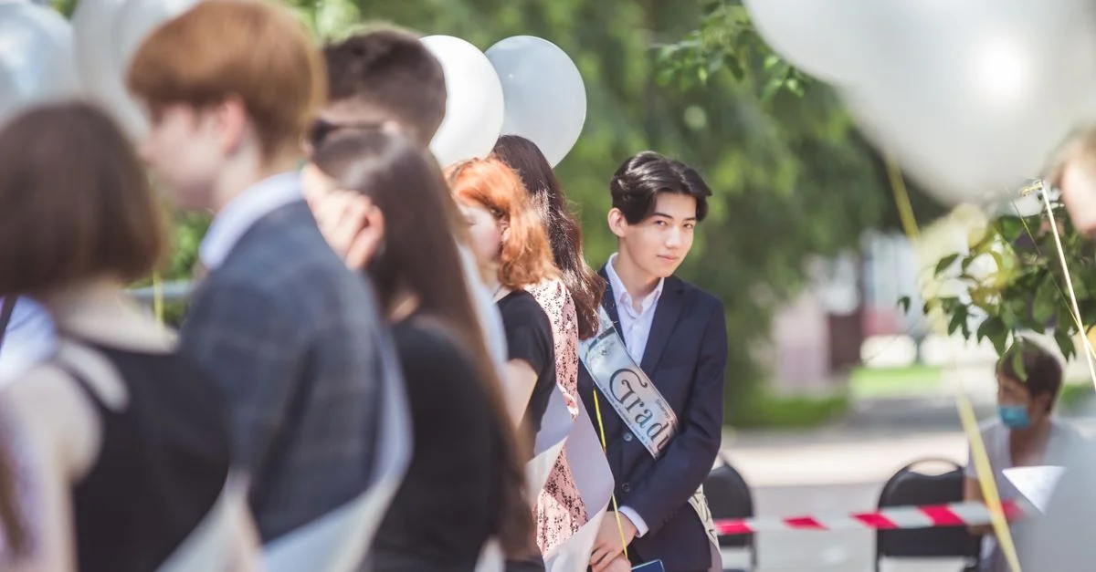 Grupo de jóvenes adultos en una ceremonia de graduación al aire libre con globos.