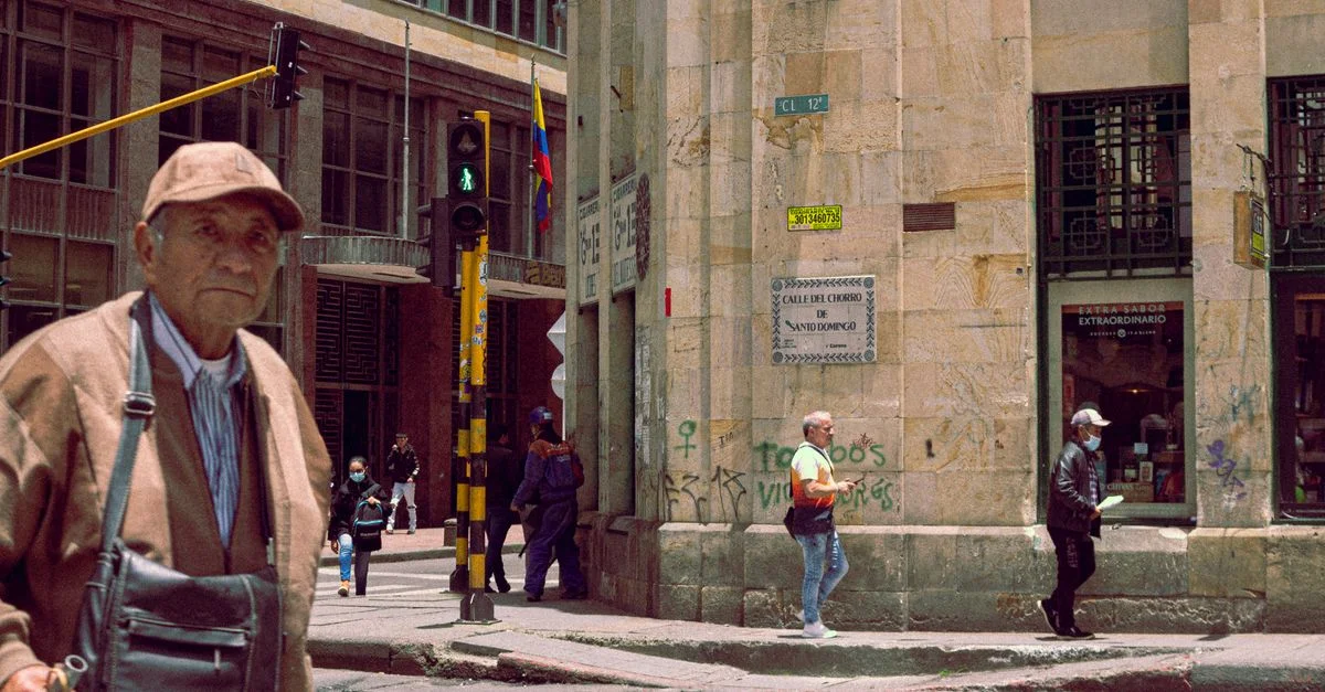 Escena urbana en Bogotá, Colombia, con peatones cruzando casualmente una intersección concurrida.